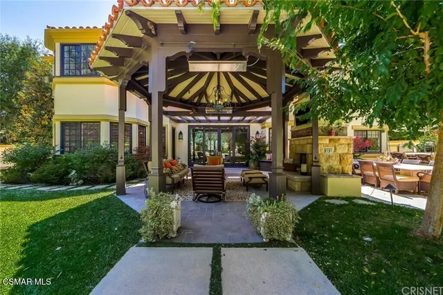 a view of a patio with a dining table and chairs under an umbrella with large trees