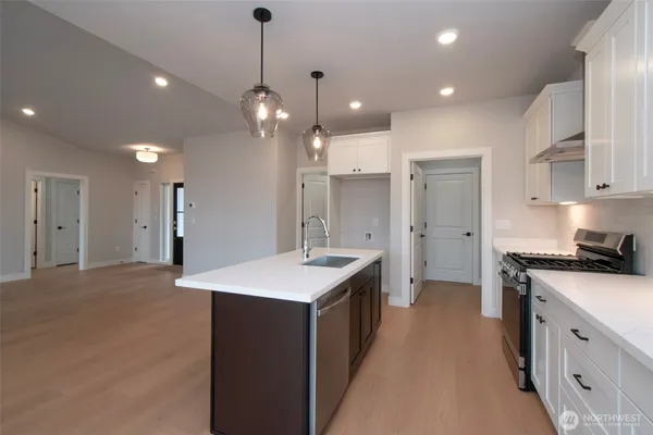 a kitchen with a sink a stove a refrigerator and white cabinets