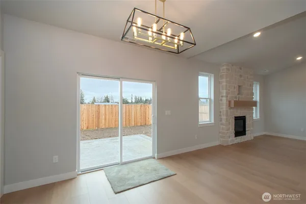 an empty room with chandelier fan and windows