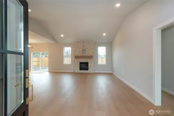 an empty room with wooden floor fireplace and windows