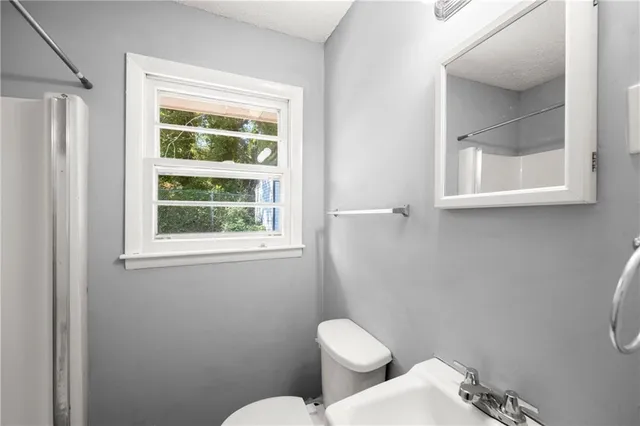 a white toilet sitting next to a window in a bathroom