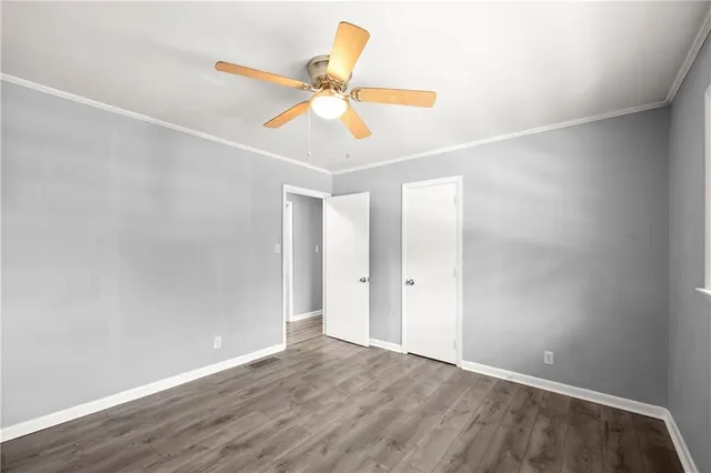an empty room with wooden floor fan and windows