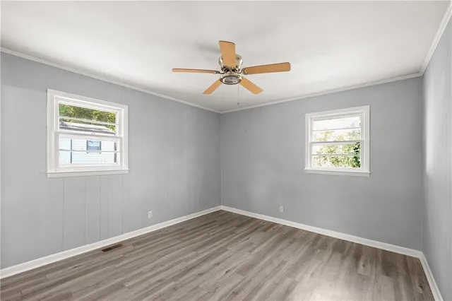 a view of empty room with wooden floor and fan