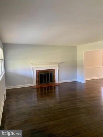 an empty room with wooden floor and fireplace