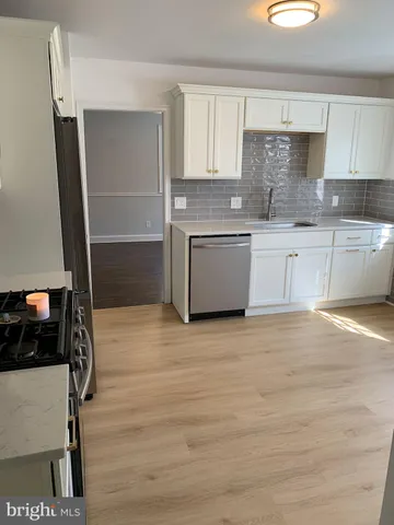 a kitchen with granite countertop a stove and white cabinets