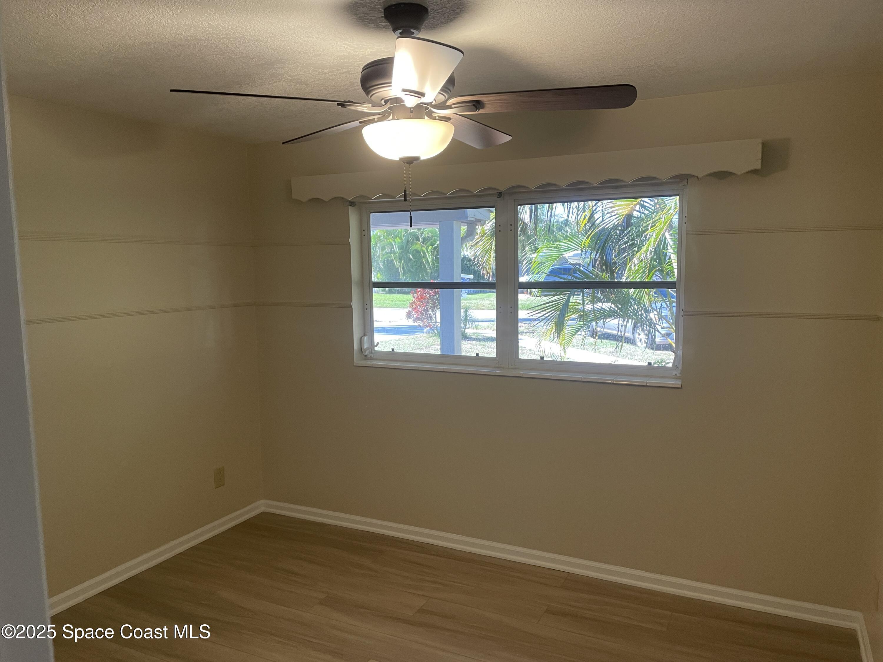104 Jupiter Court Indialantic, FL 32903 - Photo 19 of 28 an empty room with wooden floor fan and windows