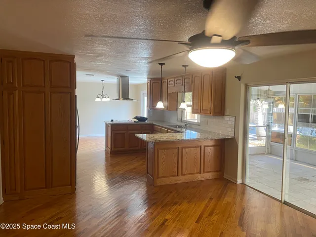 a large kitchen with kitchen island granite countertop wooden floors and a sink