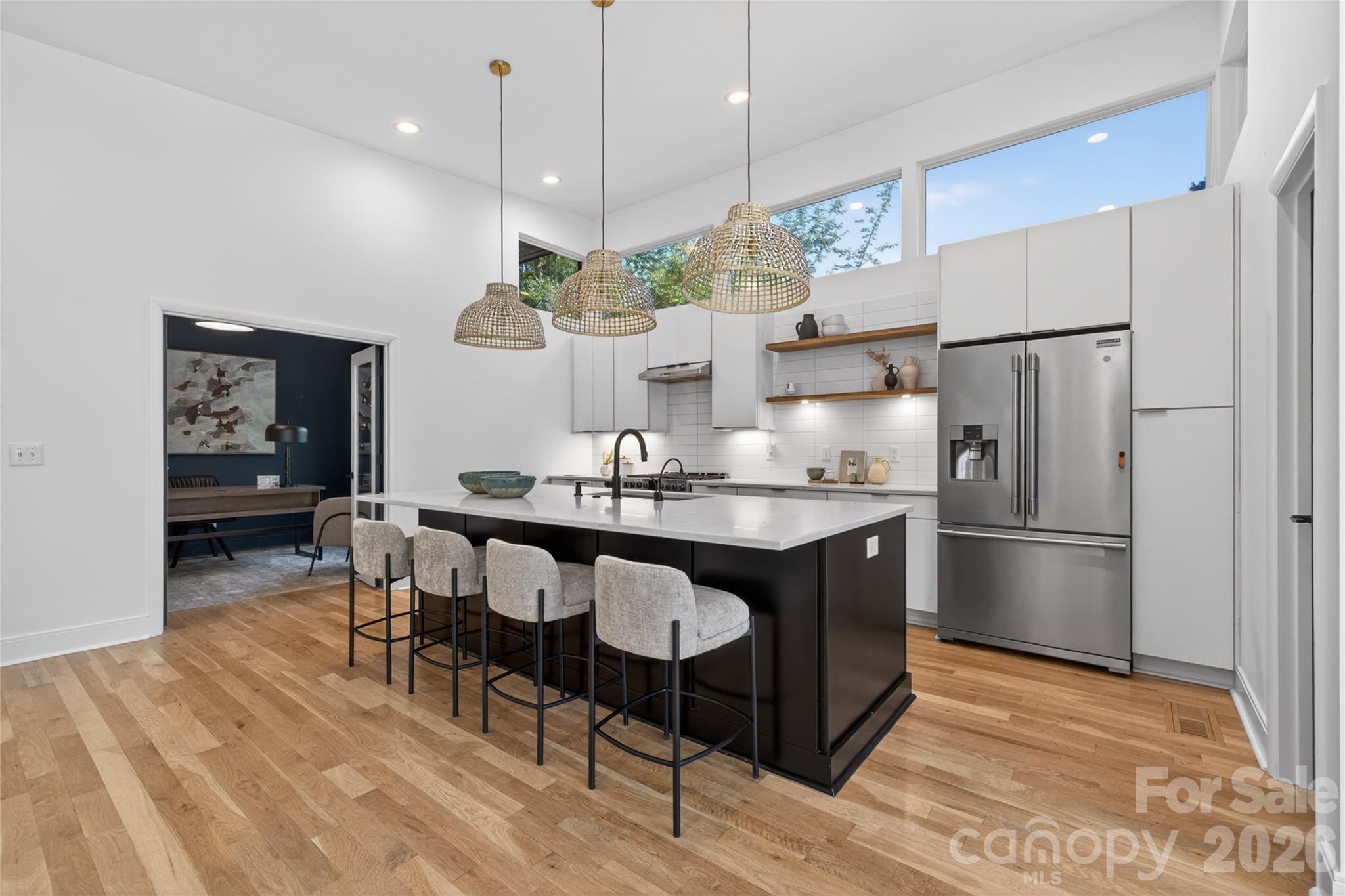 4438 Raney Way Charlotte, NC 28205 - Photo 12 of 34 a kitchen with kitchen island a refrigerator a stove a dining table and chairs with wooden floor