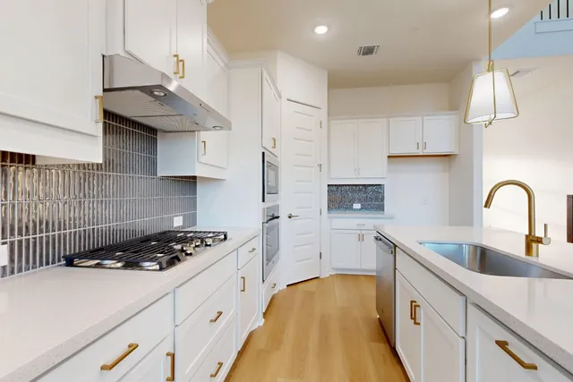 a kitchen with stainless steel appliances granite countertop a sink a stove and a refrigerator