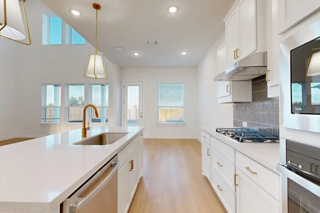 a kitchen with stainless steel appliances granite countertop a sink a stove and a wooden floors