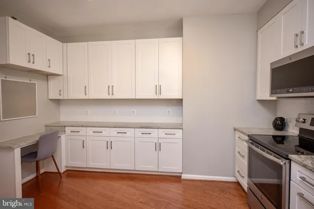 a kitchen with granite countertop white cabinets stainless steel appliances and wooden floor