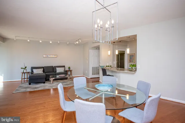 a dining room with wooden floor a chandelier a glass table and chairs