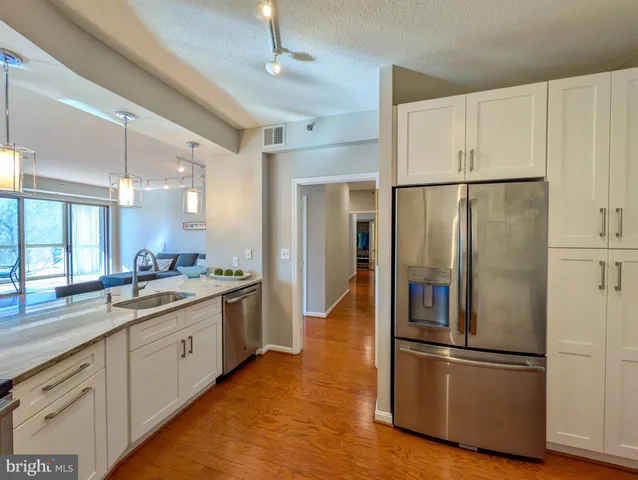 a kitchen with stainless steel appliances granite countertop a refrigerator a sink and white cabinets