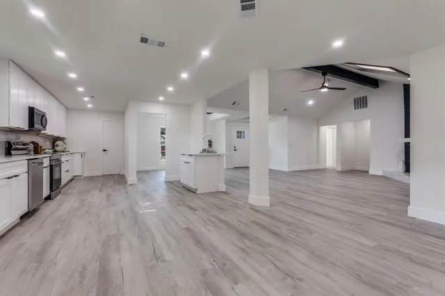 a view of an empty room and kitchen with furniture wooden floor