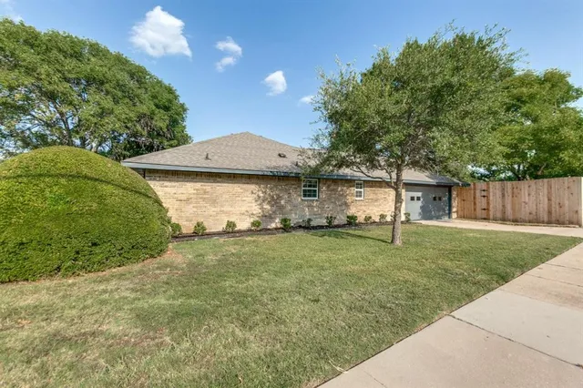 a view of a yard in front of a house with large tree