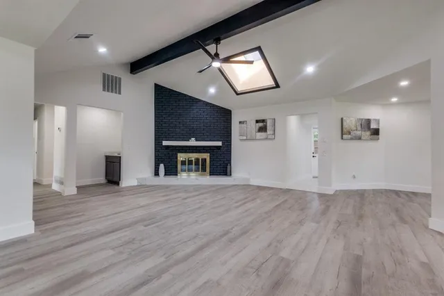 an empty room with wooden floor cabinet and windows