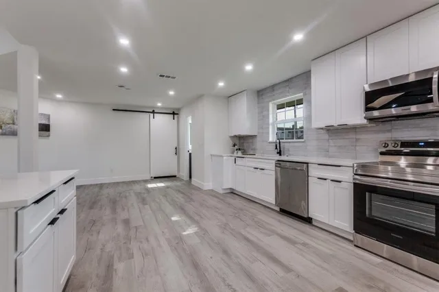 a kitchen with stainless steel appliances kitchen island granite countertop a sink cabinets and wooden floor