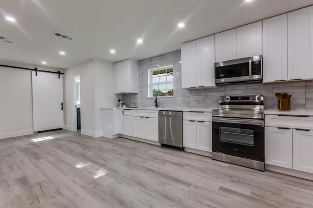 a kitchen with stainless steel appliances granite countertop a stove a sink and a microwave