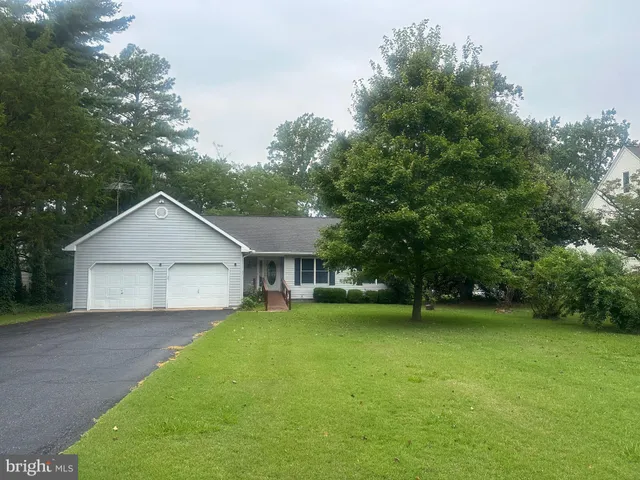a view of a house with a yard and large trees