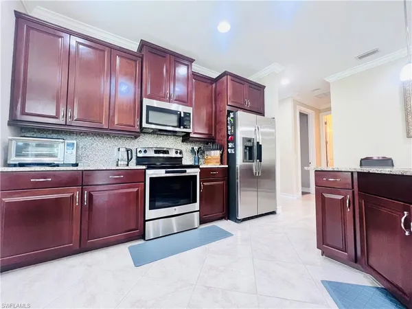 a kitchen with granite countertop wooden cabinets a stove top oven and stainless steel appliances