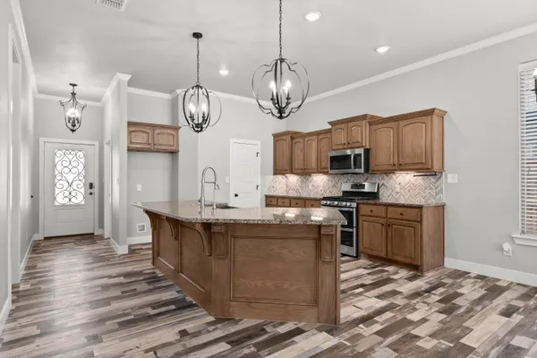 a kitchen with stainless steel appliances granite countertop a sink a stove top oven a clock and cabinets