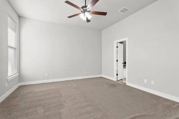 an empty room with windows and fan