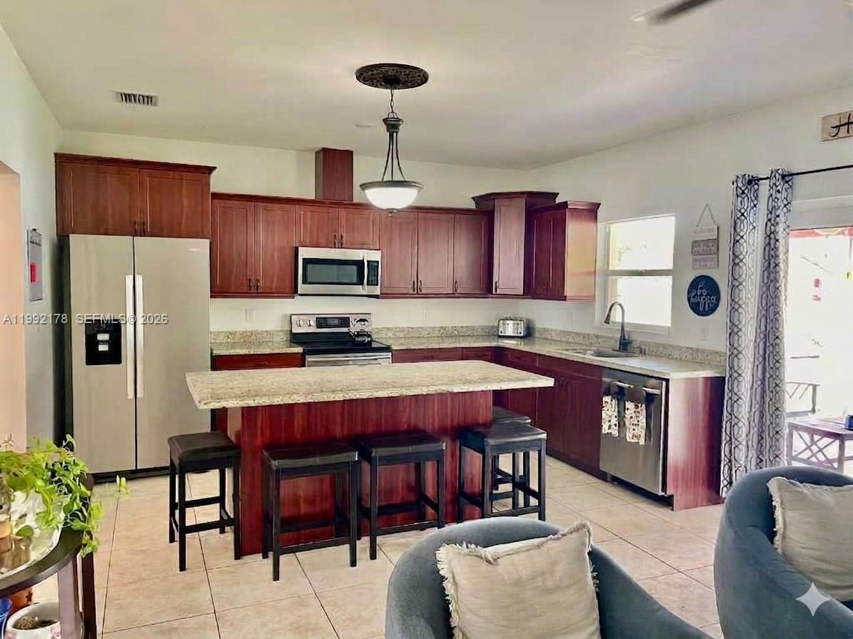 5820 Southwest 113th Court Miami, FL 33173 - Photo 5 of 22 a kitchen with stainless steel appliances granite countertop a refrigerator a stove a sink dishwasher a dining table and chairs with wooden floor
