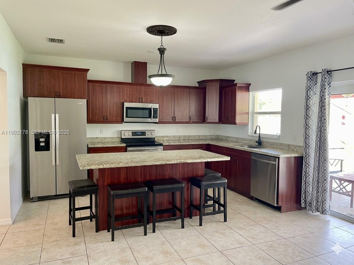 5820 Southwest 113th Court Miami, FL 33173 - Photo 6 of 22 a kitchen with stainless steel appliances granite countertop a table chairs refrigerator and microwave