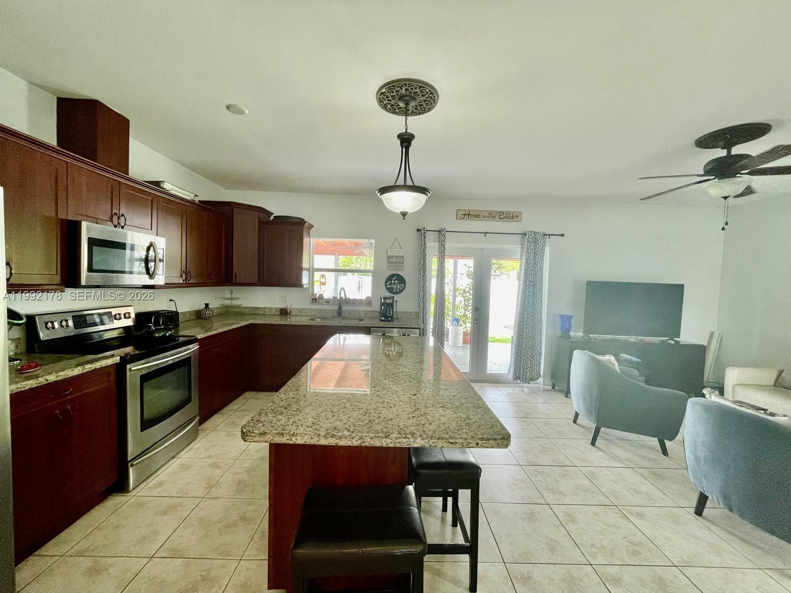 5820 Southwest 113th Court Miami, FL 33173 - Photo 7 of 22 a kitchen with stainless steel appliances granite countertop a sink dishwasher stove top oven a dining table and chairs with wooden floor