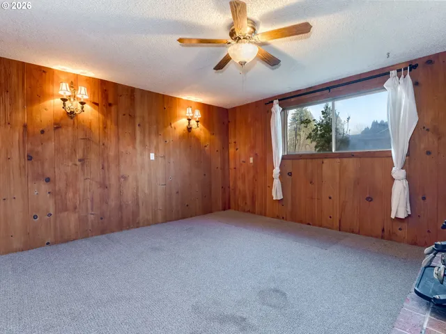 an empty room with windows fireplace and fan
