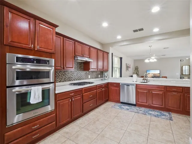 a kitchen with stainless steel appliances granite countertop wooden cabinets a stove top oven and granite counter tops