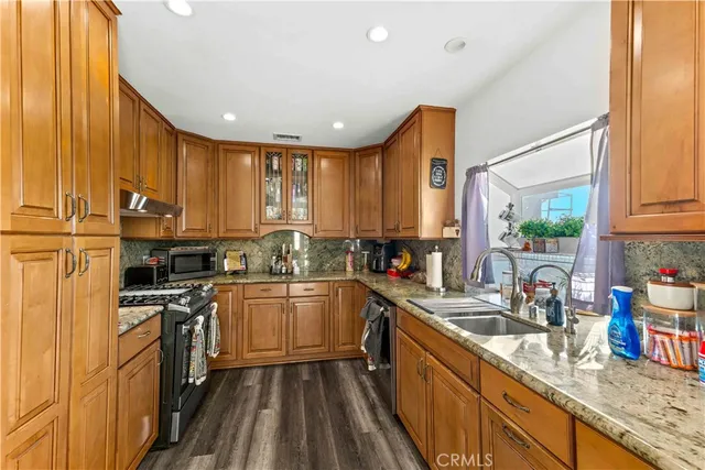 a kitchen with stainless steel appliances granite countertop sink stove top oven and cabinets