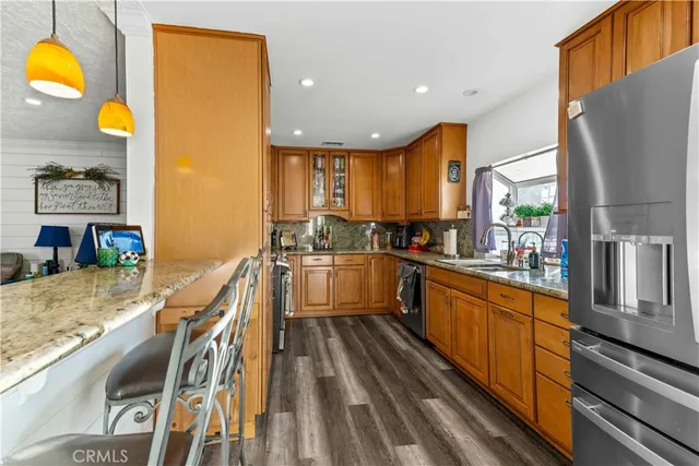 a kitchen with stainless steel appliances granite countertop a sink a stove top oven a chimney cabinets and a dining table