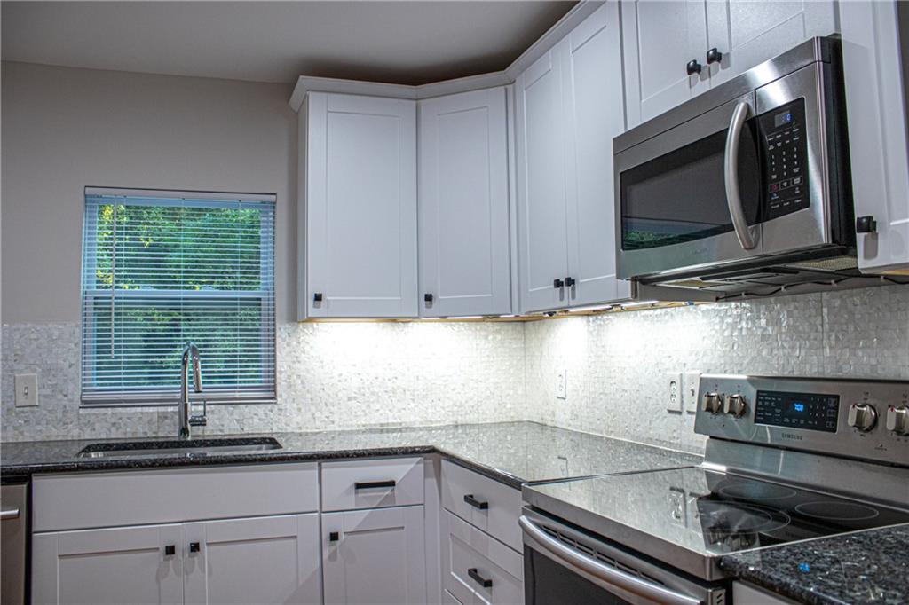 1962 Village Parkway Smyrna, GA 30080 - Photo 17 of 55 a kitchen with granite countertop a sink a stove and microwave