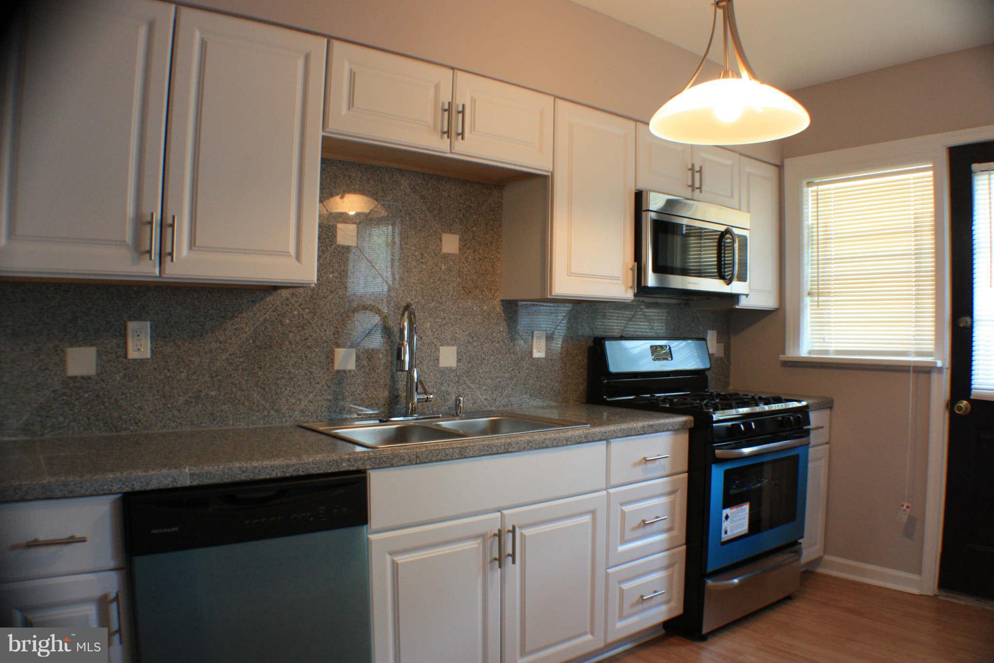 1540 Gleneagle Road Baltimore, MD 21239 - Photo 14 of 14 a kitchen with granite countertop white cabinets and white appliances