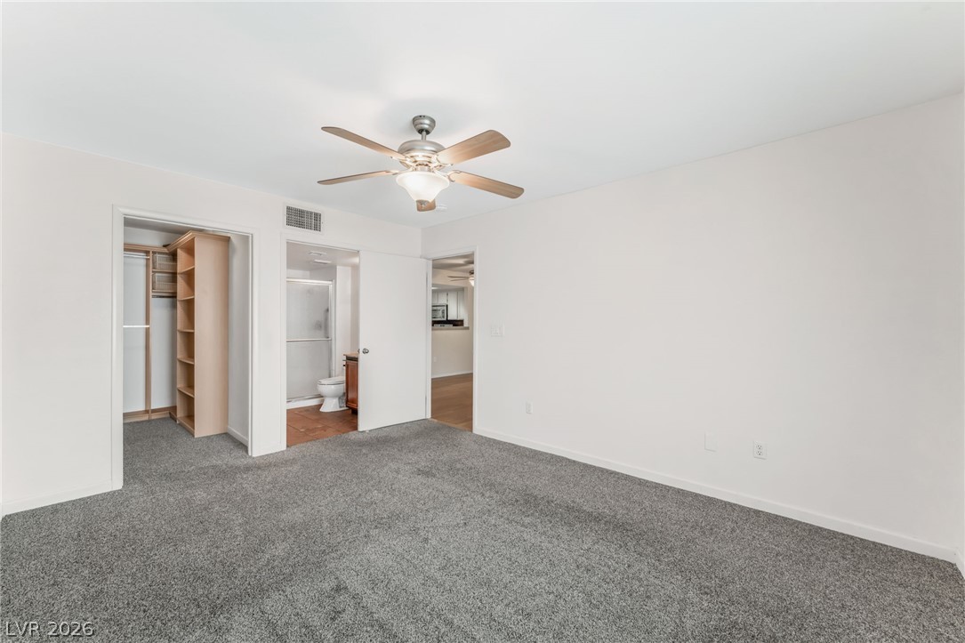 1901 Rio Canyon Court, Unit 102 Las Vegas, NV 89128 - Photo 12 of 23 A spacious sleeping area features a ceiling fan, plush gray carpet, and easy access to a private closet and bath.