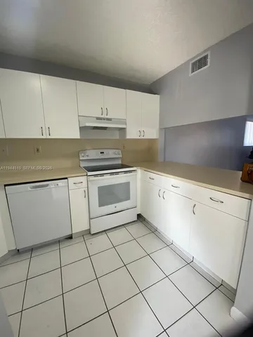 a kitchen with white cabinets a sink and white appliances