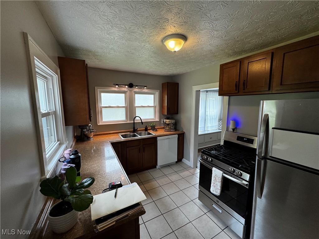 1867 South Cleveland Massillon Road Akron, OH 44321 - Photo 2 of 12 Kitchen with stainless steel appliances, baseboards, light tile patterned floors, a sink, and light countertops