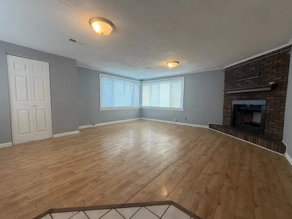 a view of empty room with wooden floor and fireplace
