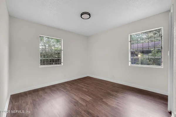 an empty room with wooden floor and windows