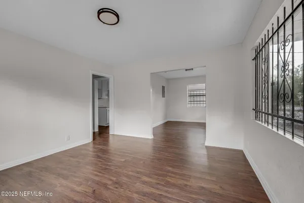 a view of an empty room with wooden floor and a window