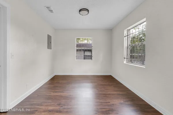 an empty room with wooden floor and windows