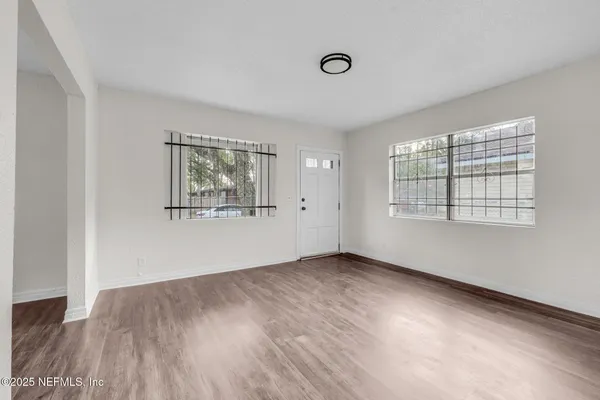 an empty room with wooden floor and windows