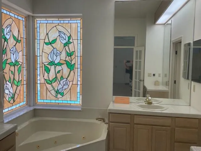 a bathroom with a granite countertop sink a mirror a bathtub and next to a window