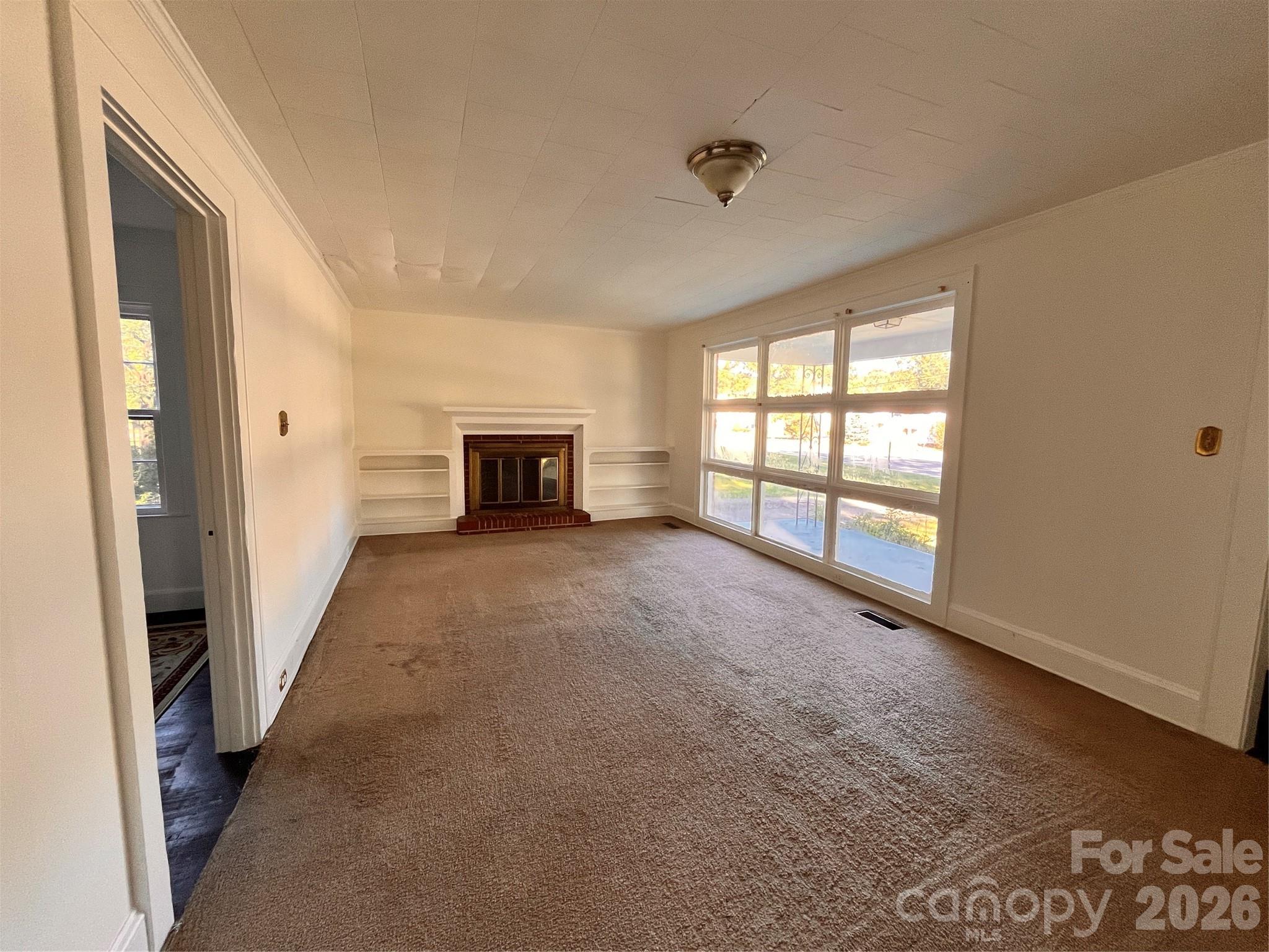 704 McAdenville Road Lowell, NC 28098 - Photo 3 of 14 an empty room with windows and fireplace