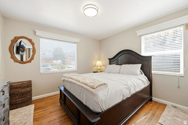 310 East 600 South Centerville, UT 84014 - Photo 12 of 41 Bedroom featuring wood-finish flooring, two windows with blinds, a ceiling-mounted light fixture, and neutral wall tones