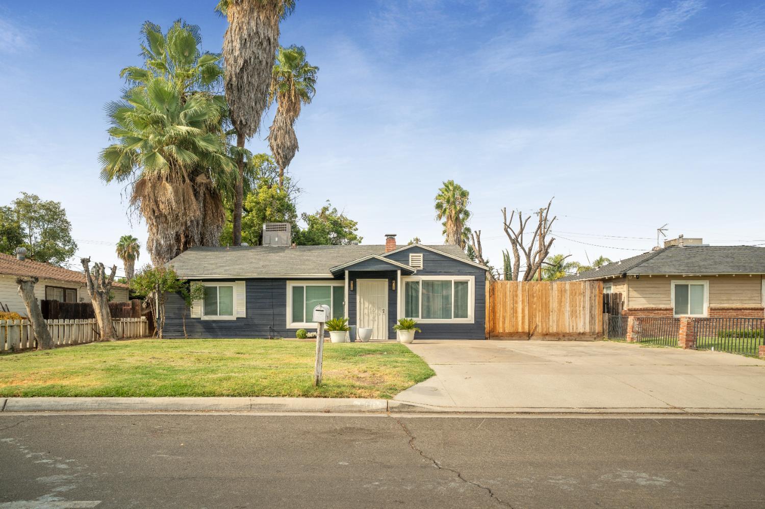 a front view of a house with a garden and palm trees