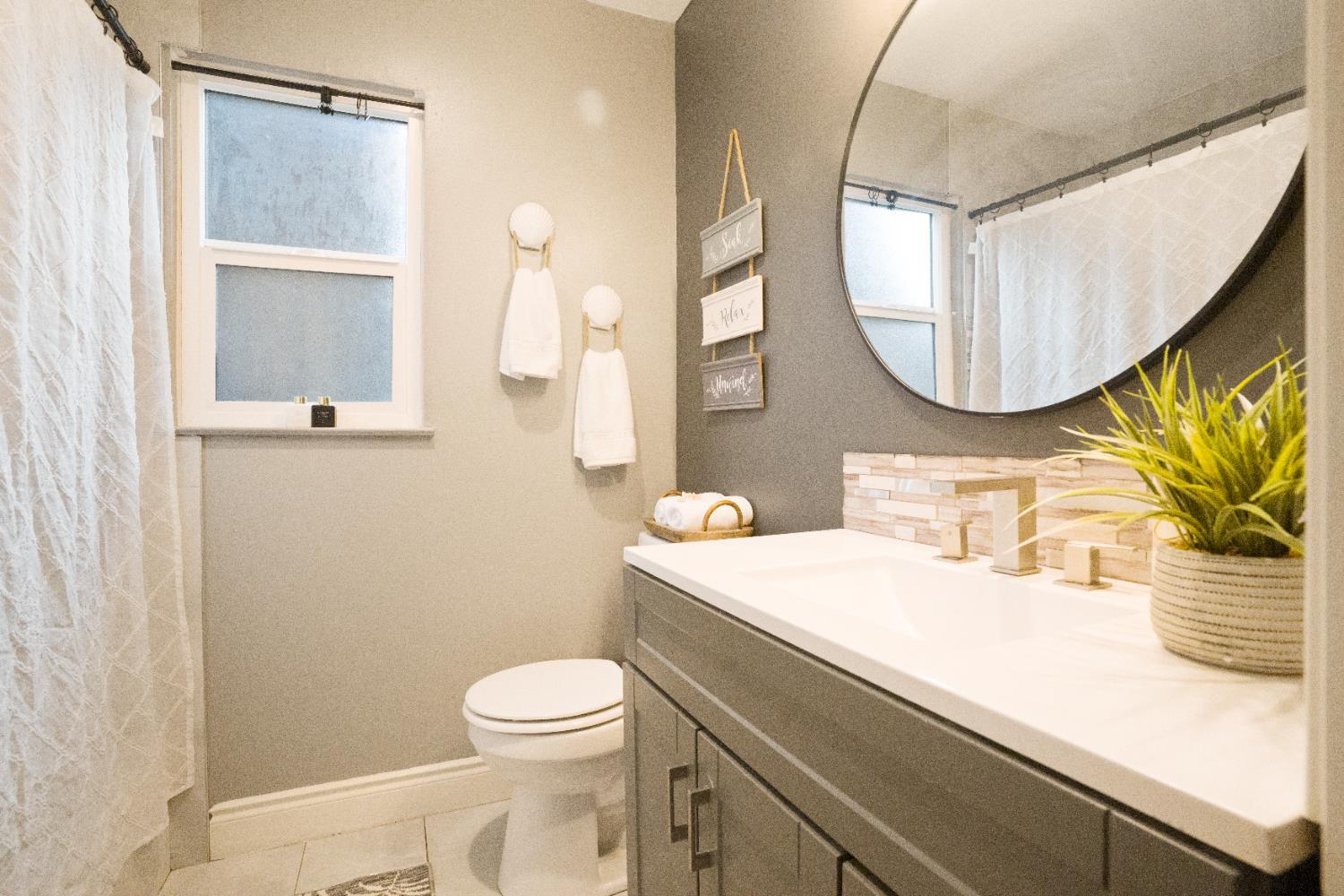 1403 East Griffith Way Fresno, CA 93704 - Photo 7 of 27 a bathroom with a sink a mirror a toilet and a mirror
