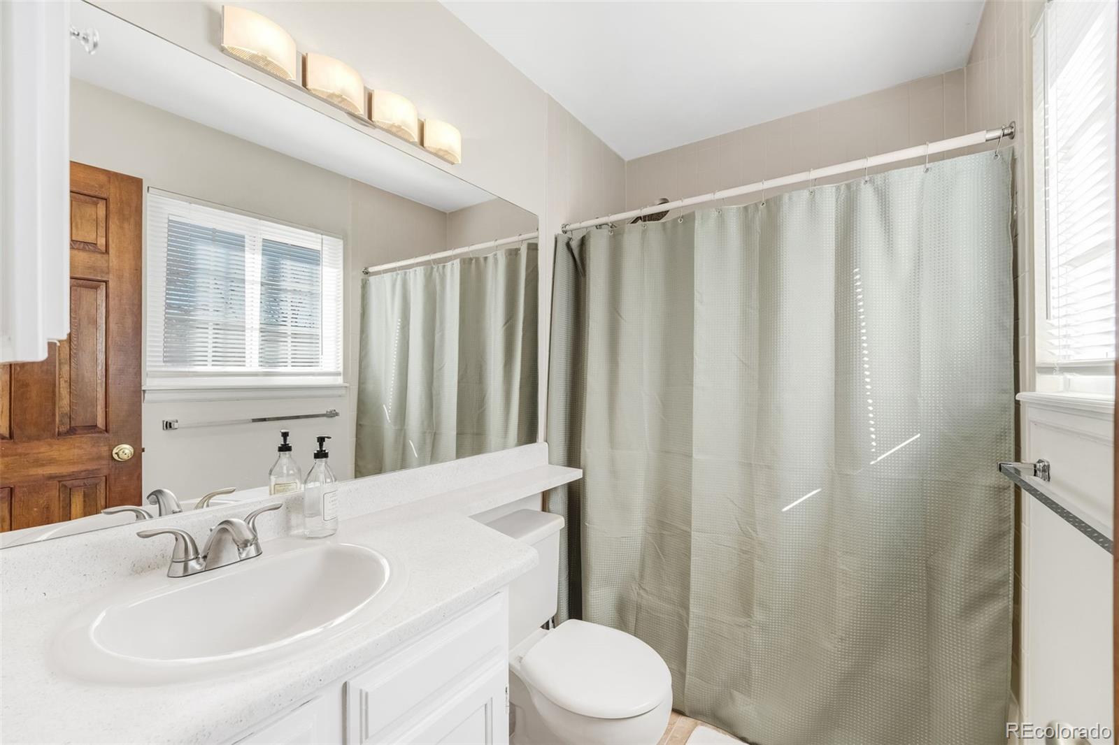 1470 South Quebec Way, Unit 282 Denver, CO 80231 - Photo 17 of 38 a bathroom with a sink a toilet and shower curtain