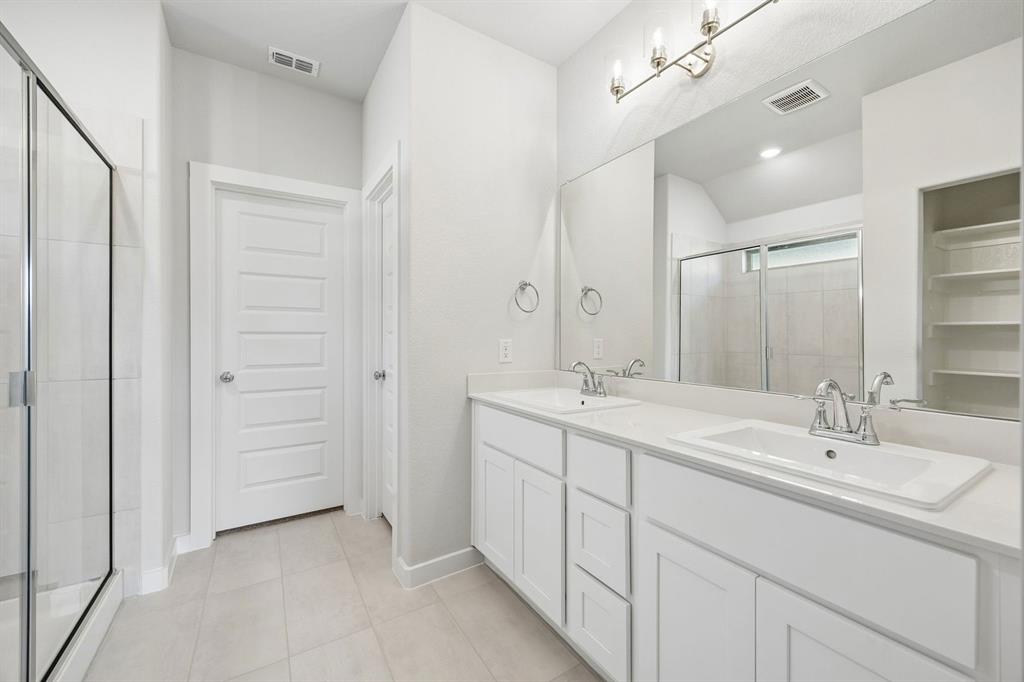 1448 Companero Street Haslet, TX 76052 - Photo 21 of 35 a bathroom with a double vanity sink a mirror and a shower